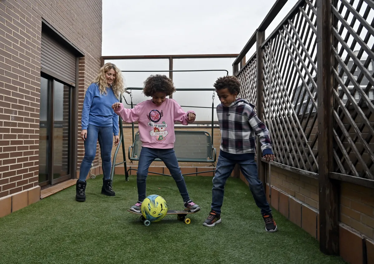 A parent and her two children playing together in their garden — homeschool life happens outside the textbook as much as inside it.